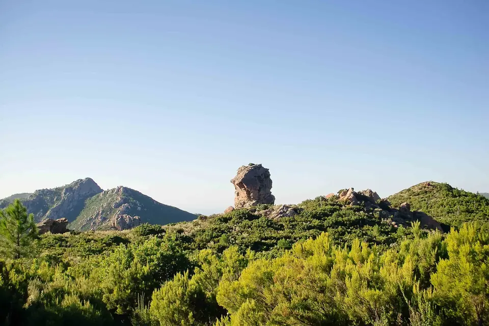 Paysage de montagne corse vu depuis le GR20 : crêtes rocheuses, aiguille de pierre et maquis sous un ciel bleu