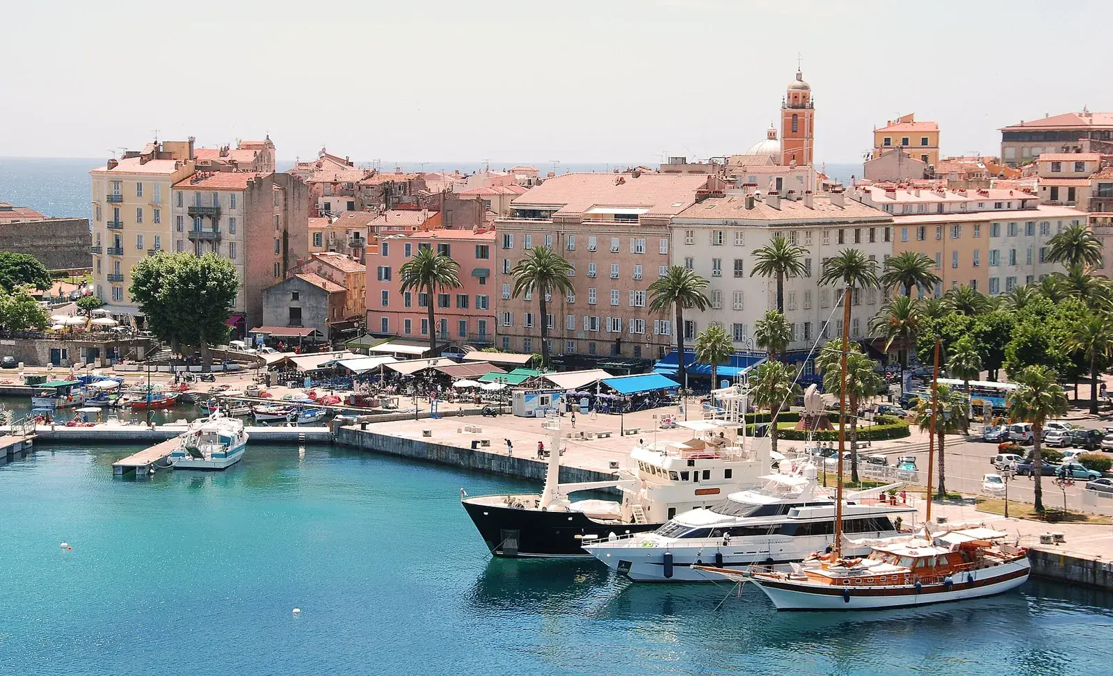 La vieille ville d'Ajaccio vue depuis la mer : immeubles ocre et roses, clocher de la cathédrale et collines en arrière-plan