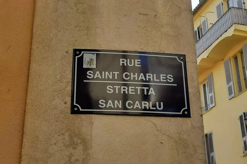 Plaque de rue bilingue sur un mur d'Ajaccio : « Rue Saint-Charles » en français et « Stretta San Carlu » en corse