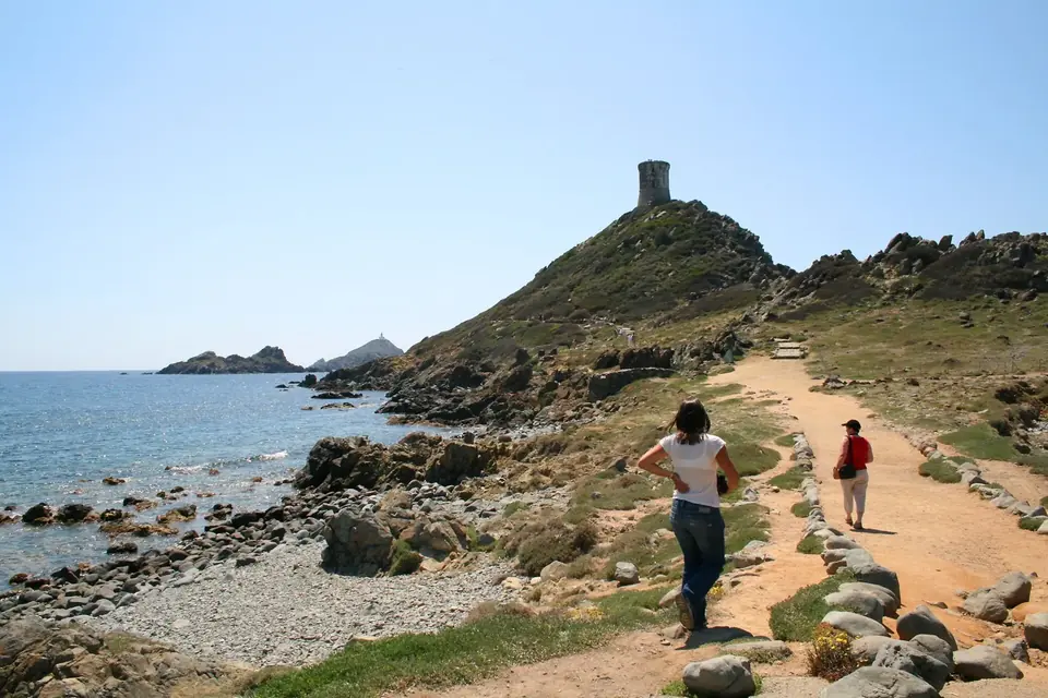 Sentier côtier menant vers la tour génoise de la Parata, au sommet d'un promontoire rocheux, avec les îles Sanguinaires au large